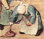 Nena remenant caca amb un pal